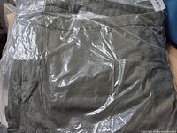 Front view of sealed green jeans in clear plastic