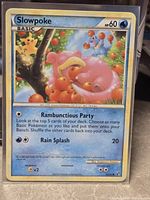 Front of Slowpoke card in sleeve showing artwork, HP 60, attacks Rambunctious Party & Rain Splash
