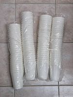 Four stacks of white cups inside two sealed sleeves