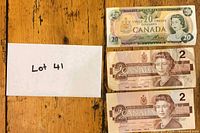 Overview of three banknotes on wooden surface ($20, two $2)