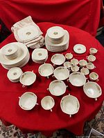 Overall set showing stacks of plates and rows of handled cups on red cloth