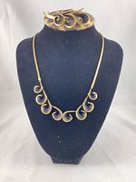 Necklace displayed on bust, swirl link pattern visible