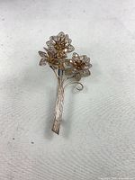 Front view of silver-tone floral filigree brooch with two flowers and stem