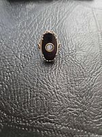 Front view of ring showing oval black stone and central bezel