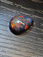 Pear-shaped black opal showing intense multicolour fire