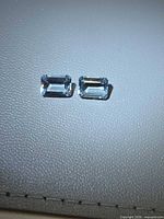 Two emerald-cut aquamarines on light background
