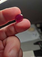 Ruby held between fingers showing overall shape and face-up appearance