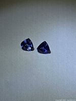 Pair of deep blue pear-cut tanzanite gemstones on neutral background