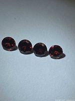 Four round faceted red garnets displayed side by side