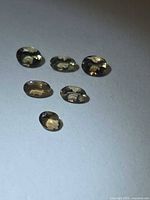 Six oval champagne Tanzanite stones on flat surface