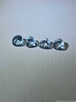 Four pear-cut light blue aquamarines aligned side by side on neutral background