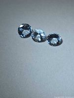 Three round faceted aquamarines on neutral background