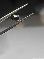 Octagon-cut purple spinel held by tweezers showing faceting