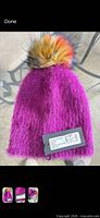 Full view of plum angora hat with multicolor faux fur pom and tags