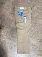 Full view of beige Haggar slacks laid flat showing overall condition