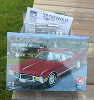 Front of sealed AMT Classic 1969 Buick Riviera kit with loose Impala parts visible behind