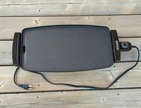 Top view of full griddle showing cooking surface, handles and power cord