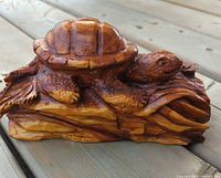 Front view of glossy wooden turtle on carved base