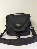 Front view of Lowepro camera bag showing logo, flap, buckle and shoulder strap