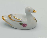 Left profile view of porcelain duck showing floral motif and gold trim