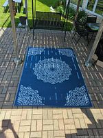 Full view of blue side of carpet laid on patio showing mandala pattern and overall size
