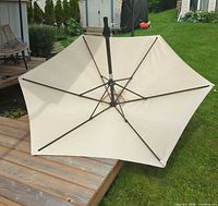 Umbrella fully opened on deck showing beige canopy and metal ribs