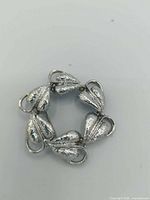 Front view of silvertone wreath brooch showing five leaf elements and circular form