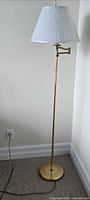 Full view of brass floor lamp with pleated shade and cord