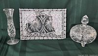 Full view of three clear cut crystal pieces: bud vase, rectangular tray, covered candy dish