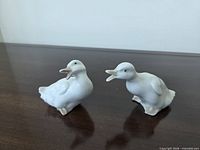 Front view of two white porcelain duck figurines