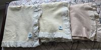 three folded wool blankets showing colors and satin bindings