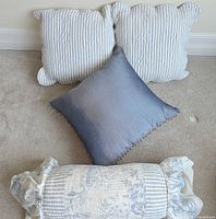 Front view of two striped scalloped pillows, gradient blue pillow and toile bolster pillow
