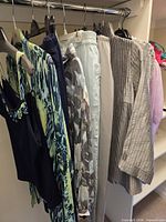 Multiple tops and pants hanging on rack showing variety of prints, colours and fabrics