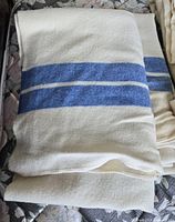 Folded cream wool blankets showing blue stripe pattern