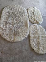 Overview of three cream oval shag rugs on floor