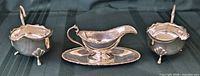 front view of gravy boat on underplate between two sauce boats