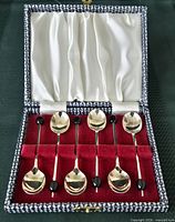 Open case showing six spoons arranged in red velvet interior