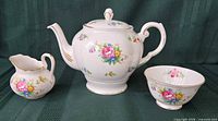 Front view of teapot, creamer and sugar bowl showing full set and pattern