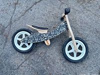 Side view of balance bike showing full frame, wheels, and graphic deck