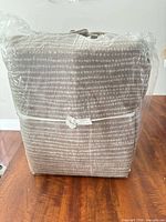 Plastic-wrapped bundle of taupe and gray striped fleece sheet set