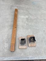 Wood post alongside two steel post bases on concrete
