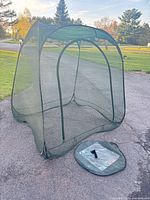 Full view of assembled green mesh pop-up screen tent on driveway