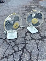 Both Hampton Bay table fans side by side on pavement