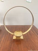 Front view of circular brass candle holder on wood surface