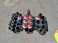 Three plastic bottle caddies, some holding white bottles with red caps, shown on pavement