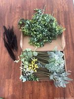Box holding assorted green artificial stems with yellow, white accents