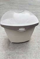 Front view of off-white plastic compost bin with gray perforated hinged lid
