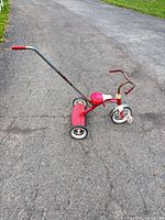Full side view of red Radio Flyer tricycle with push handle
