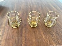 Three matching brass-finish tealight holders on table