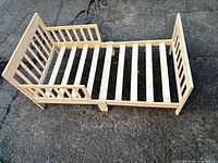 Overall view of solid wood toddler bed frame with slats and guard rails